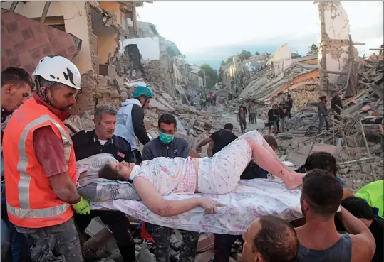  ??  ?? Survivor: Rescuers carry an injured woman in the historic town of Amatrice, which was devastated by Wednesday’s earthquake