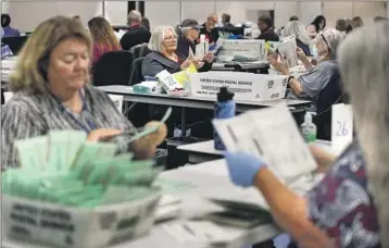  ?? Gina Ferazzi Los Angeles Times ?? ELECTION workers look over ballots at the Maricopa County vote counting center in Phoenix.