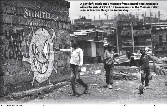  ?? Photo: AFP ?? A boy (left) reads out a message from a mural warning people about the risk of COVID-19 transmissi­on in the Mathare valley slum in Nairobi, Kenya on Wednesday.