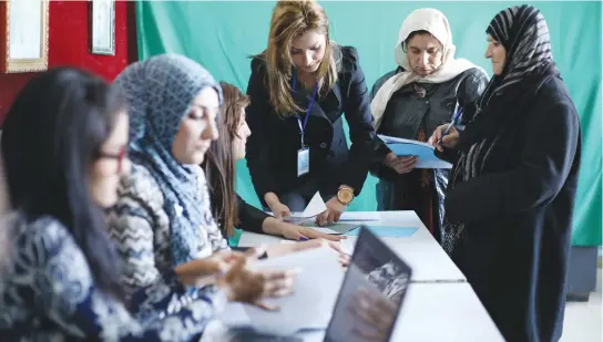  ?? (Rodi Said/Reuters) ?? SYRIAN KURDS register their names before voting at a polling station in Qamishli, Syria, in December.