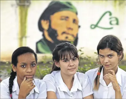  ?? EFE / ALEJANDRO ERNESTO ?? El futur Tres estudiants davant d’un mural amb la imatge de Fidel Castro, ahir a l’Havana.