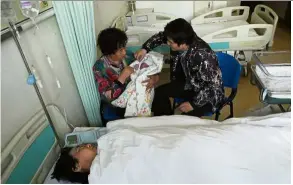  ?? — China Daily/Asia News Network ?? Special delivery: Zheng resting in bed as her family members watch over her newborn son at Peking University Third Hospital in Beijing.