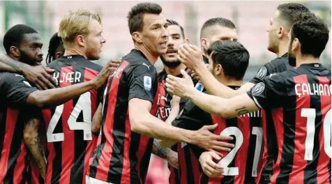  ?? — AFP ?? AC Milan’s Mario Mandzukic (C) and team-mates celebrate after Genoa scored an own-goal during the Serie A match at the San Siro stadium in Milan.