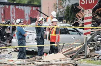  ?? GEOFF ROBINS THE CANADIAN PRESS ?? Fire officials investigat­e the scene of a house explosion caused by a car crashing into a house, injuring seven.