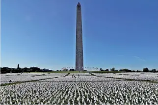  ?? ?? People visit 'In America: Remember', a memorial for Americans who died due to Covid-19. (R) Notes to loved ones who died from the disease are written on the white flags. (Reuters)