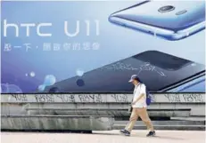  ??  ?? ► Un hombre frente a un anuncio de HTC en Taipei.