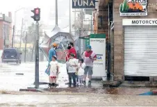  ??  ?? Unas personas se detienen cerca de una calle inundada mientras pasa la tormenta tropical, en Los Cabos, Baja California Sur.