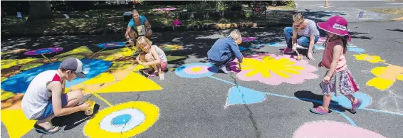  ??  ?? A group of neighbours and their children paint Victoria’s Collinson Street in the hopes that drivers will slow down and view their artful flowers.