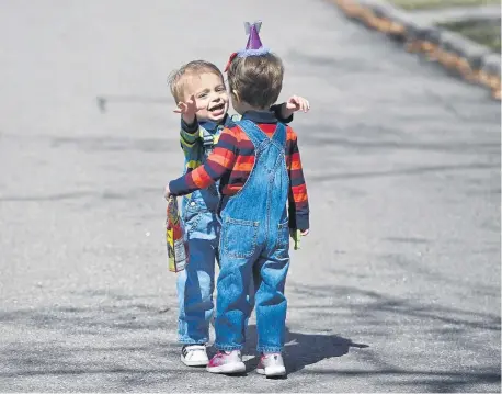  ?? Photos by Andy Cross, The Denver Post ?? Maxwell Freed, 3, left, gives his twin sister, Riley, a hug in front of their University Park home in Denver during their March 27 birthday party, which included social distancing from well-wishers because of the coronaviru­s pandemic.