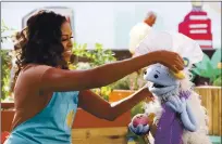  ?? ADAM ROSE — NETFLIX VIA AP ?? Former first lady Michelle Obama puts a chef’s hat on Waffles, a furry puppet with waffle ears and holding Mochi, a pink round puppet, on the set of the children’s series “Waffles + Mochi.” Obama is launching the new Netflix children’s food show on March 16.