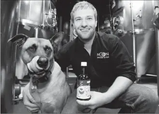  ?? ADRIAN LAM, TIMES COLONIST ?? Clay Potter, a co-owner and brewmaster of Moon Under Water, with his four-year-old dog Brew and one of the brewpub’s new non-alcoholic canine beers.