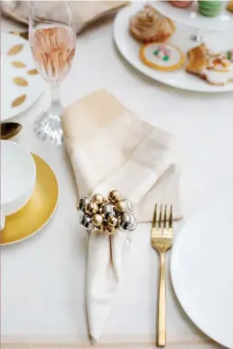  ??  ?? RIGHT & BELOW
For Christmas cheer, there’s champagne – pink, of course, to complement the home’s pink-and-gold holiday loveliness. Fine woven linens are slipped though jingle-bell inspired napkin rings. The flatware and china feature elements of gold, worthy of an English high tea.