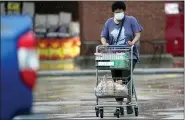  ?? DAVID J. PHILLIP — THE ASSOCIATED PRESS ?? A shopper wears a mask as she pushes her grocery cart in the rain Thursday in Houston.