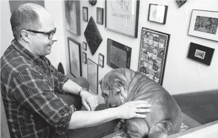  ??  ?? John Porcellino pets his dog, Iris, at his home in Beloit, Wisconsin, on March 3.