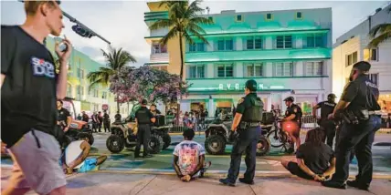  ?? MIAMI HERALD ?? Miami Beach police officers detain three men on Ocean Drive across from the Avalon Hotel during Spring Break in Miami Beach on Saturday.