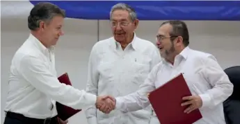  ??  ?? Cuba's President Raul Castro (C) looks on as Colombia's President Juan Manuel Santos (L) shakes hands with FARC rebel leader Rodrigo Londono, better known by Timochenko, after signing a historic ceasefire deal between the Colombian government and FARC...