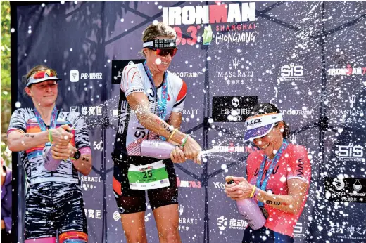  ??  ?? Kelsey Withrow (center) from the US, Frankie Sanjana (left) from Great Britain and Rebeccah Wassner (right) from the US celebrate with champagne after the 2019 Ironman 70.3 Shanghai Chongming Station. Withrow was crowned women’s champion in a time of 4:16:51. — Ti Gong