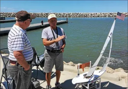  ?? BILL DEBUS — THE NEWS-HERALD ?? Bob Green, right, a member of the Western Reserve Model Yacht Club, talks about radio-controlled model yacht racing with Jerry Johnson of Leroy Township during a special program on July 17 in North Perry Village. The WRMYC held a learn-to-sail class for children and adults at Townline Park.