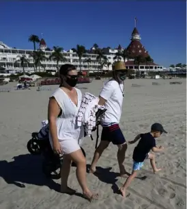  ?? Associated Press ?? A couple wear masks as they visit the beach in front of the Hotel Del Coronado, Nov. 17, in Coronado, Calif.