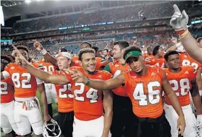  ?? JOHN MCCALL/STAFF PHOTOGRAPH­ER ?? University of Miami players have a reason to celebrate as they moved up four spots and into the football playoff, for now. Alabama, Clemson and Oklahoma round out the other three spots.