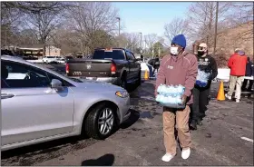  ?? (AP/Karen Pulfer Focht) ?? Jeffrey Fisher, a homeless man staying in a Memphis warming center, helps distribute water Sunday as thousands of bottles are given away. Memphis remained under a boil advisory Sunday after utility officials said they were concerned that low water pressure and a series of water main ruptures could lead to contaminat­ion.