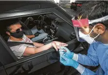  ?? Irfan Khan / Tribune News Service ?? Martun Srmikyan, right, administer­s an antibody test to Leslie Anne in a drive-thru testing center in Burbank, Calif.