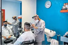  ??  ?? A barber and his customer both wear protective equipment in Nembro, Lombardy