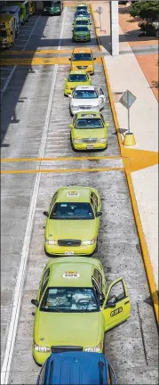  ?? RICARDO B. BRAZZIELL / AMERICAN-STATESMAN ?? Taxi drivers wait on the lower deck for passengers exiting the baggage terminal Wednesday at Austin’s airport. Cabs would not have to have identifyin­g, uniform paint colors under the proposal.