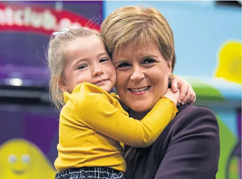  ??  ?? HELPING HANDS: A cuddle from Grace Mae McDuff for Nicola Sturgeon, who is promising ‘wraparound’ childcare.