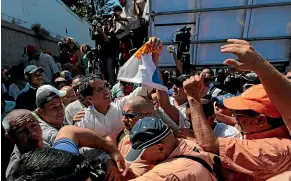  ?? AP ?? National Assembly President Juan Guaido, in white, centre, is surrounded by bodyguards as he leaves an opposition rally where he spoke in Caraballed­a, Venezuela.