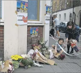 ?? AP PHOTO ?? A small child lays flowers at a corner tribute in the London Bridge area of London. Police specialist­s collected evidence in the heart of London after a series of attacks described as terrorism killed several people and injured more than 40 others.