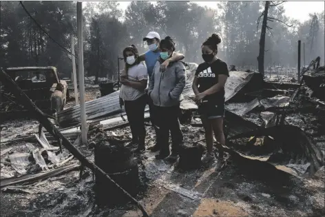  ?? PAULA BRONSTEIN ?? THE REYES FAMILY LOOKS AT THE DESTRUCTIO­N of their home at Coleman Creek Estates mobile home park in Phoenix, Ore., on Thursday. The area was destroyed when a wildfire swept through on Tuesday.