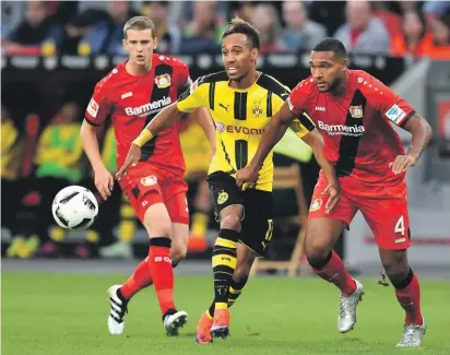  ??  ?? Dortmund's Pierre-Emerick Aubameyang, center, and Leverkusen's Jonathan Tah, right