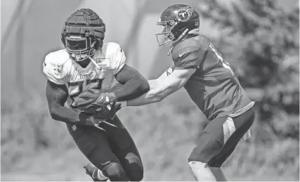  ?? ANDREW NELLES/THE TENNESSEAN ?? Titans quarterbac­k Ryan Tannehill hands off to running back Derrick Henry during a joint practice with the Vikings in Eagan, Minn., on Aug. 17.