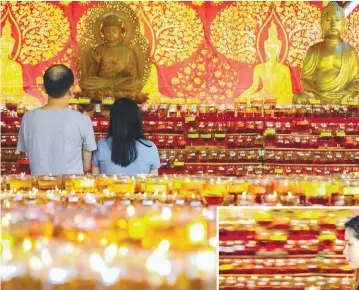  ?? AMIRUL SYAFIQ MOHD DIN / THESUN ?? Devotees praying at the Thai Buddhist Chetawan temple yesterday. Inset: A woman lighting a lamp at the Thai Buddhist Chetawan temple to celebrate Buddha's birthday.