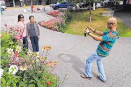  ?? DAN JOLING/ ASSOCIATED PRESS ?? Junar Lim takes photos of Ziah Lim, left, and Arsenia Lim, all of Cavite, the Philippine­s, at Town Square in Anchorage, Alaska, Thursday. The city hit 90 degrees on July 4,
5 degrees higher than its previous record.
