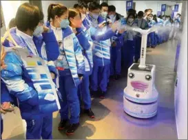  ?? PROVIDED TO CHINA DAILY ?? Staff members at the National Stadium in Beijing interact with a robot that cleans and disinfects Olympic venues.