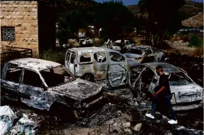  ?? AHMAD GHARABLI/AFP VIA GETTY IMAGES ?? A man walked around burned out cars, reportedly set ablaze by Israeli settlers, in the area of in Al-Lubban Al-Gharbi in the occupied West Bank on Wednesday.