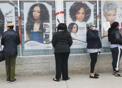  ?? (Shannon Stapleton/Reuters) ?? PEOPLE WEAR face masks waiting outside a beauty salon and check cashing facility in the Highland Park section of Detroit in April.