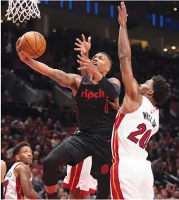  ?? (Reuters) ?? PORTLAND TRAIL BLAZERS guard Damian Lillard scores against Miami Heat defender Justise Winslow (right) for two of his game-high 32 points in the Blazers’ 115-99 home victory over the Heat on Monday night, extending Portland’s winning streak to 10 games.