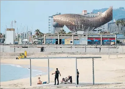  ?? ALEJANDRO GARCÍA / EFE ?? Agentes de la Guardia Urbana informan sobre la prohibició­n de tomar el sol en la playa de Barcelona