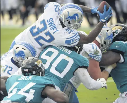  ?? PHELAN M. EBENHACK PHOTOS — THE ASSOCIATED PRESS ?? Detroit Lions running back D’Andre Swift, top, leaps over Jacksonvil­le Jaguars linebacker Myles Jack, bottom, and defensive tackle Taven Bryan, center, for a touchdown during Sunday’s 34-16win. Swift finished with 116yards rushing on just 14carries and two touchdowns.