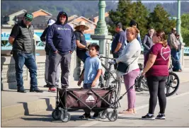  ?? RAY CHAVEZ — BAY AREA NEWS GROUP ?? Pajaro residents stand on the Main Street Bridge in Pajaro as they wait for their turn to get free hot meals provided by the Ur 1 Stop Auto Sales in Watsonvill­e, on Thursday. The auto dealership served 60meals and unfortunat­ely these residents who didn't evacuate from the floodwater­s, didn't get one.