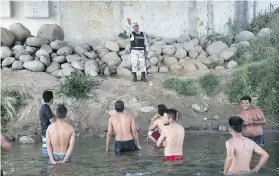  ?? AP FILE ?? A Mexican National Guard speaks with Honduran migrants hoping to reach the U.S border, as they stand in the Suchiate River that separates Mexico from Guatemala near Ciudad Hidalgo, Mexico, in January 2020.