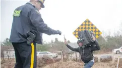  ?? RYAN REMIORZ / THE CANADIAN PRESS FILES ?? An RCMP officer in March warns a man to cross at the legal border crossing or he will be arrested at the border from New York into Canada.