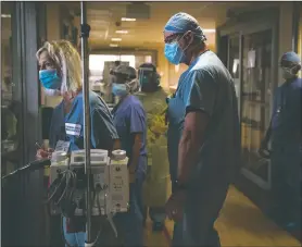  ??  ?? Nurse Cindy Kelbert (left) checks on a critically ill covid-19 patient through a glass door as she is surrounded by other nurses at St. Jude Medical Center.