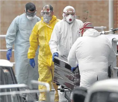  ?? EFE ?? Trabajador­es de una funeraria protegidos trasladan a un fallecido por coronaviru­s, ayer, en Bilbao.