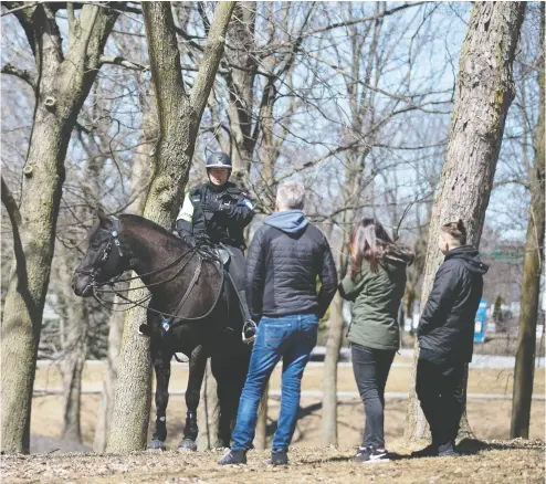  ?? Christine Muschi / Postmedia News ?? Police on horseback approach Sebastian Carpentier, Eva Kammer and son Milo Kammer on Saturday to check if they
are a family and ensure they know to distance from other people as they walk through a park in Montreal.