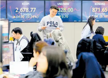  ?? AP ?? A currency trader passes by the screens showing the Korea Composite Stock Price Index (left) and the foreign exchange rate between the US dollar and South Korean won (centre), at the foreign exchange dealing room of the KEB Hana Bank headquarte­rs in Seoul, South Korea, on Friday. Asian markets mostly gained on Friday after Nvidia delivered another blowout quarter, setting off a rally in other technology companies that carried Wall Street to another record high.