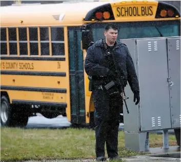  ?? PHOTO AFP ?? Un policier armé d’un fusil d’assaut monte la garde devant un des autobus utilisés pour transporte­r les élèves hors du périmètre du collège de Great Mills High.